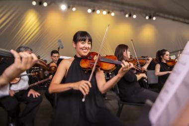 violinist smiling while playing in orchestra