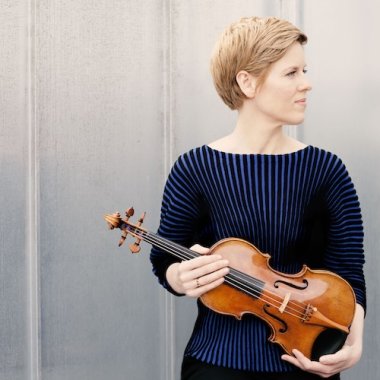 white woman in blue sweater holding a violin.