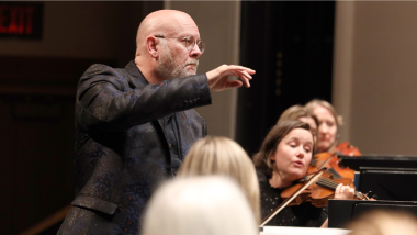 A man conducts a string orchestra.