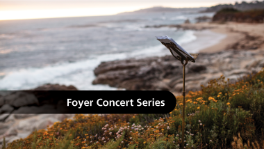 A music stand on a path above the beach with the text, "Foyer Concert Series."