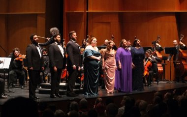 Members of the Rising Stars of Opera stand on stage singing to the audience.