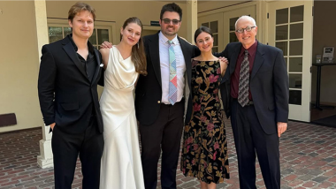Four people stand with their arms around each other, wearing formal concert dress.