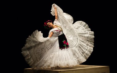 Dancer with a big white skirt is holding the skirt while twirling