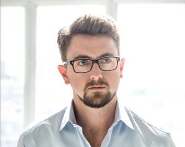 A portrait of a man with a beard and glasses.