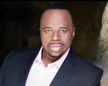 A headshot of man with a tuxedo who is looking directly at the camera. 