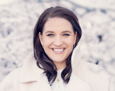 A woman smiling at the camera in front of a white background.