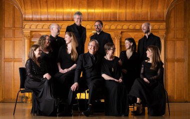 The Tallis Scholars posing in front of a wooden ornate wall