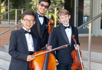 Colburn Community School string students smiling for a photo with their instruments.
