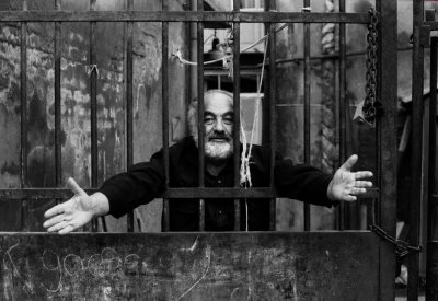 Sergei Parajanov with outstretch arms behind bars.