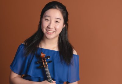 Violinist Charisse Chao in a blue dress against a rust background