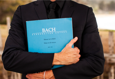 A person holds a blue book of some of Bach's works.