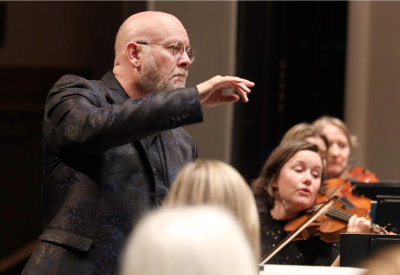 A man conducts a string orchestra.