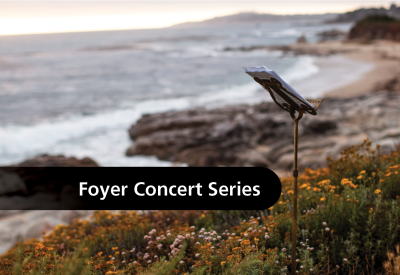A music stand on a path above the beach with the text, "Foyer Concert Series"