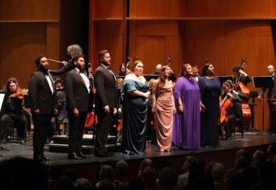 Members of the Rising Stars of Opera stand on stage singing to the audience.