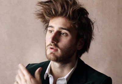A portrait of a man, who is looking to the side, in front of a beige backsplash.