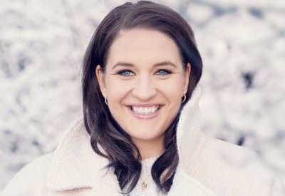 A woman smiling at the camera in front of a white background.