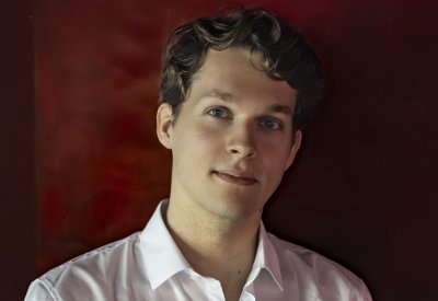 Lukas Sternath is looking into the camera and is pictured in front of a dark red background