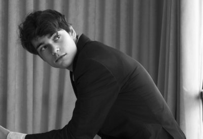 The photo is in gray scale. Tom Borrow is sitting and looking besides the camera.